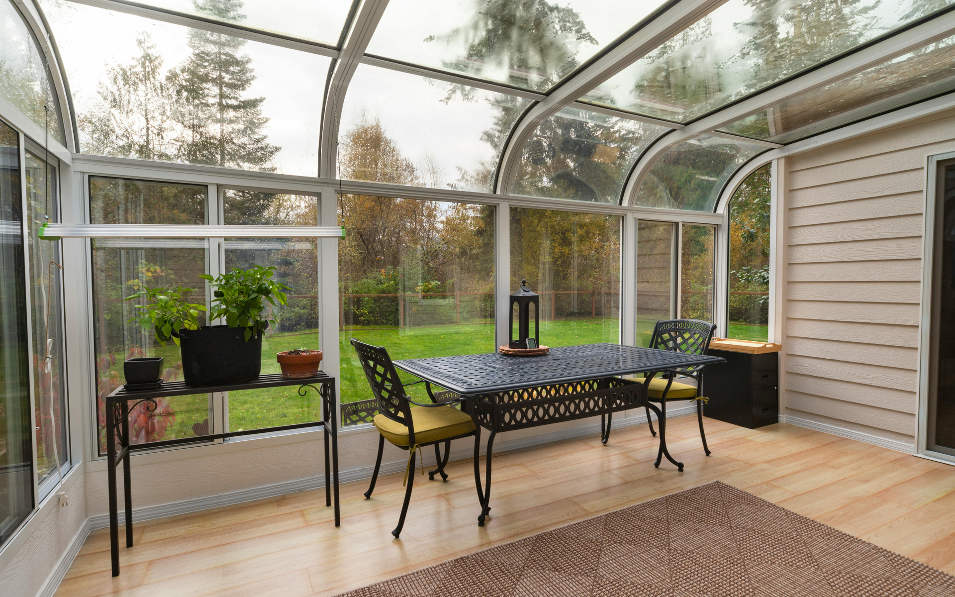A sunroom with a table and chairs and a glass roof.