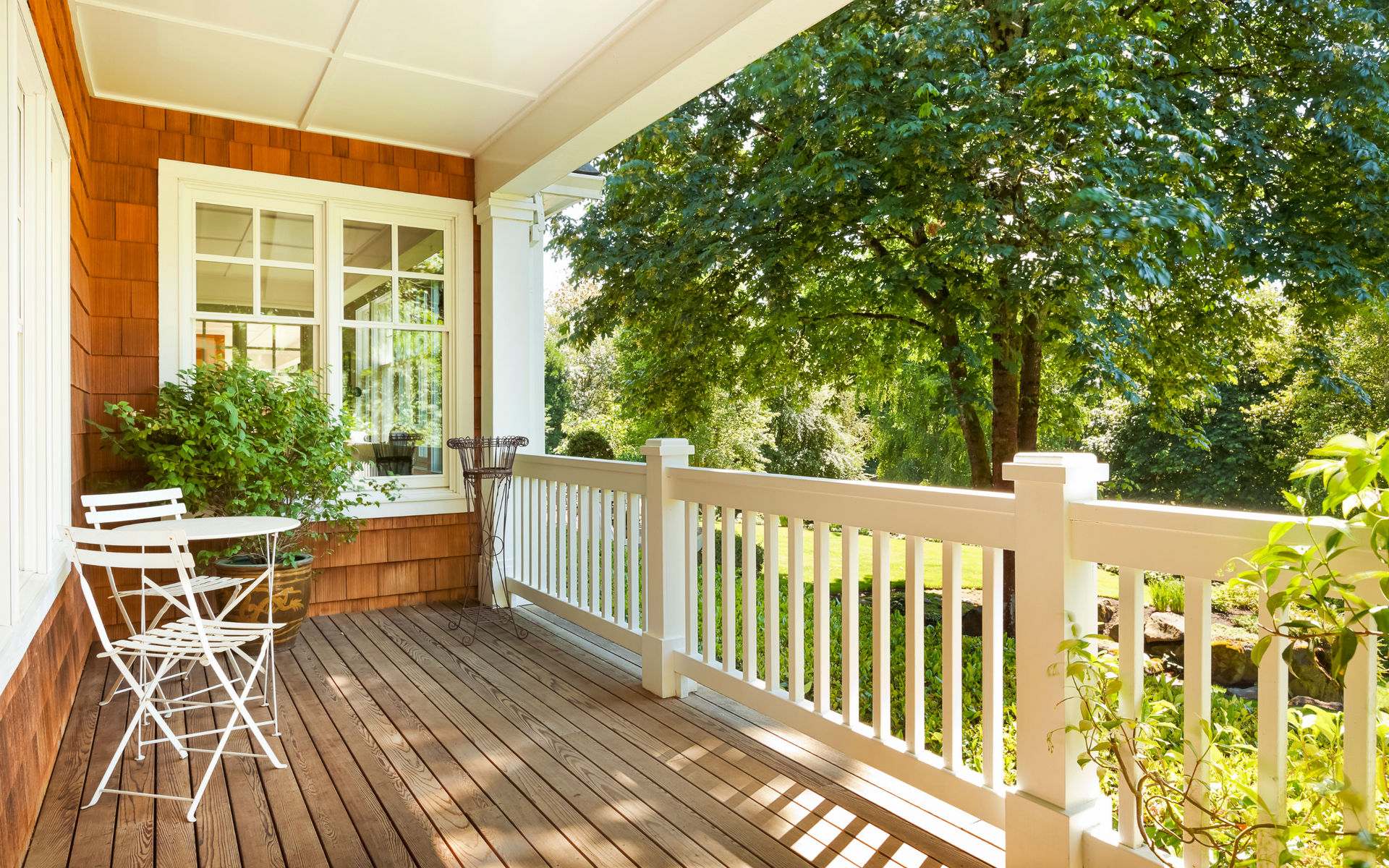 There is a porch with a table and chairs on it.