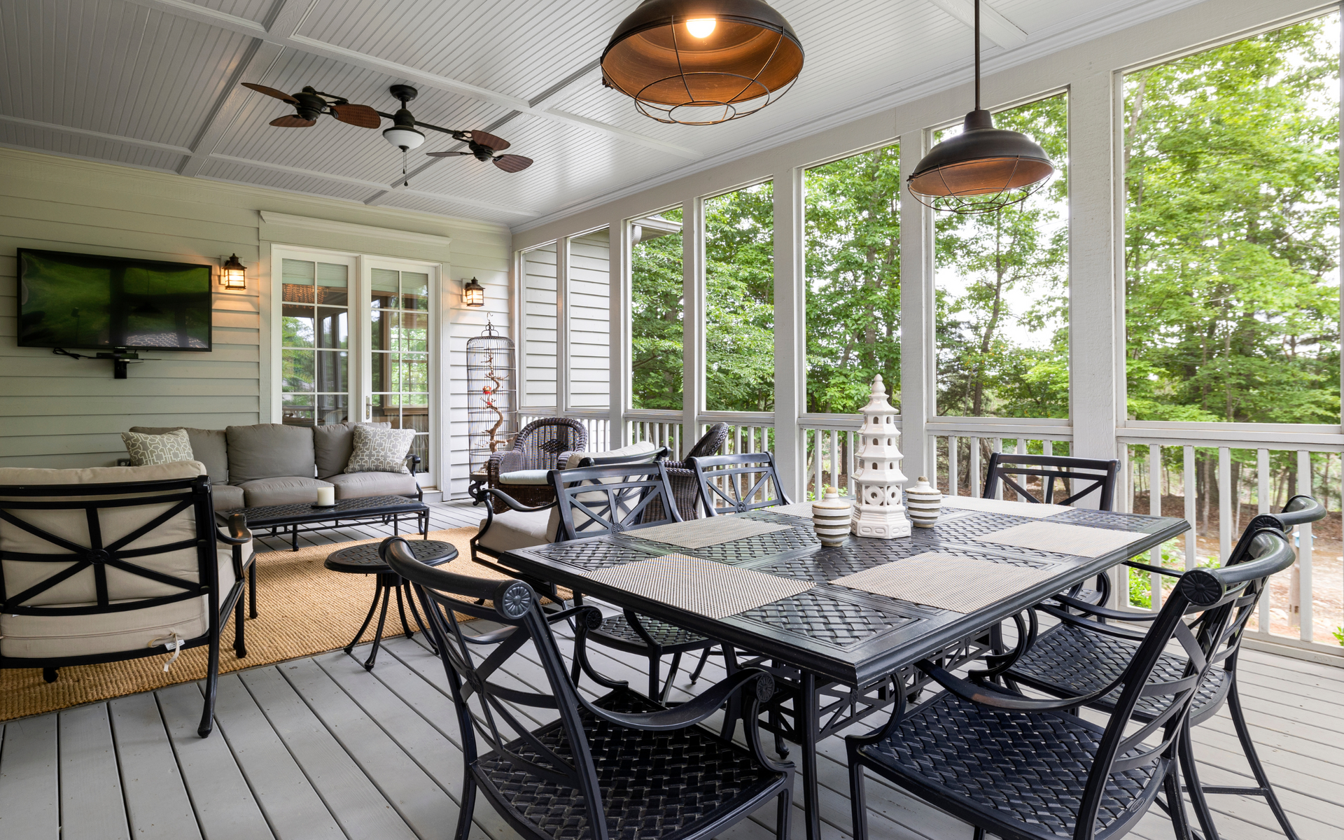A screened in porch with a table and chairs and a television.