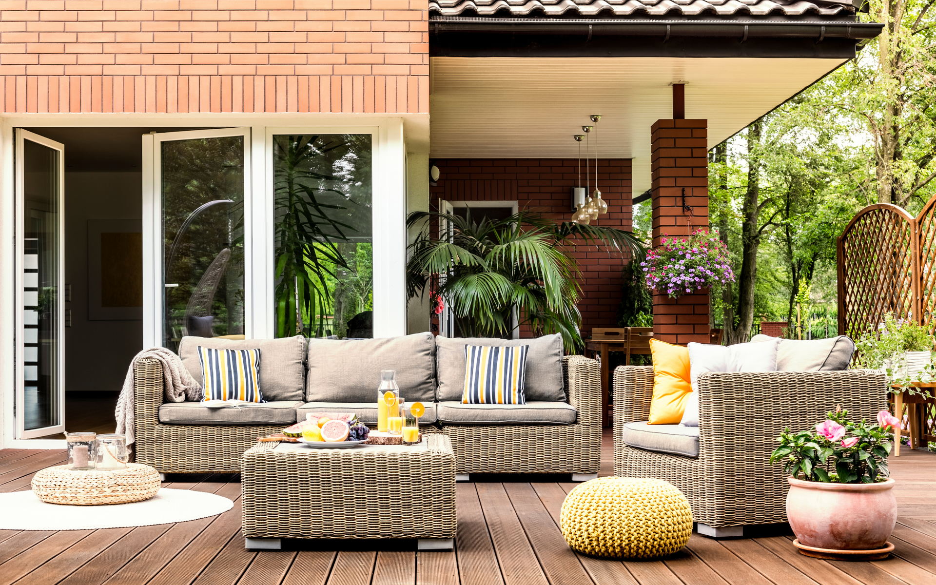 A patio with wicker furniture and a couch on a wooden deck.