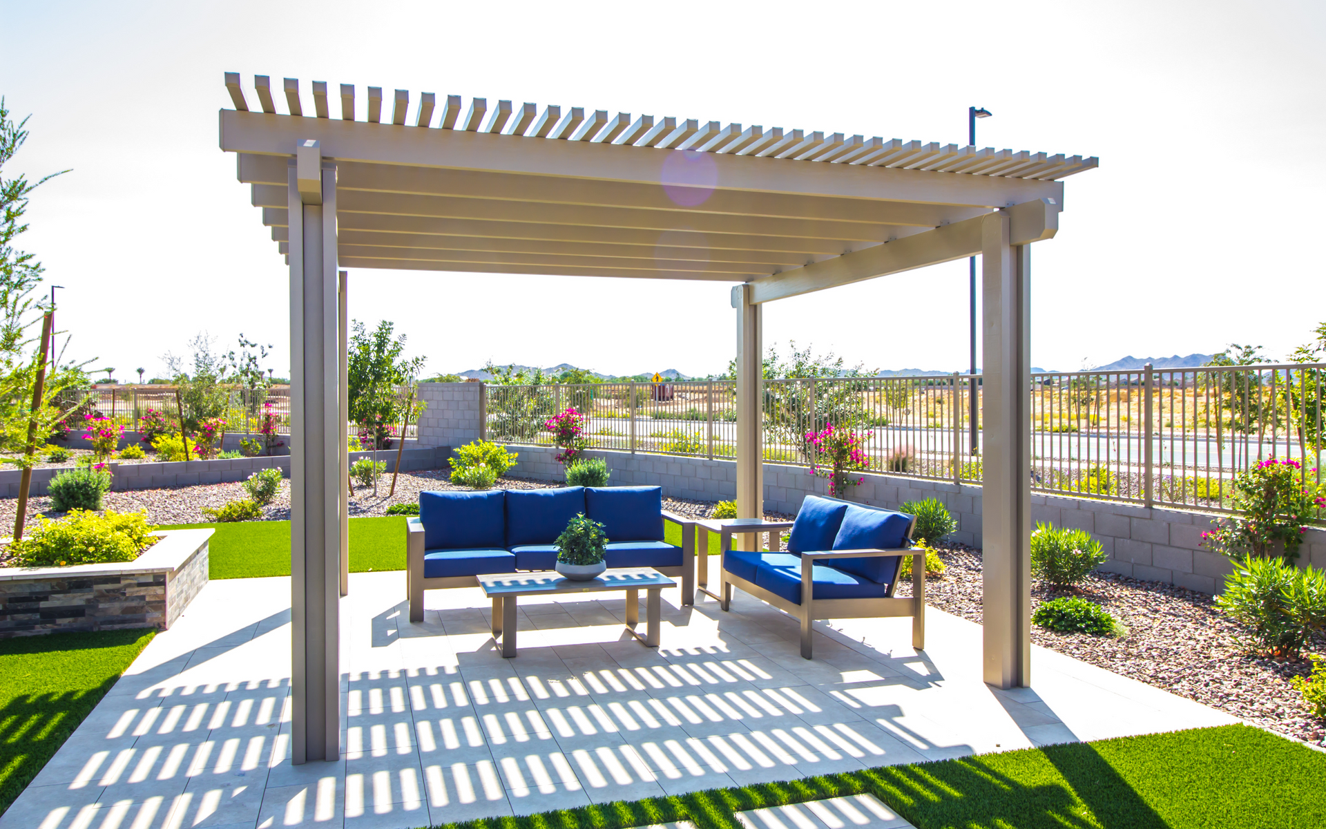 There is a pergola with a couch and chairs underneath it.