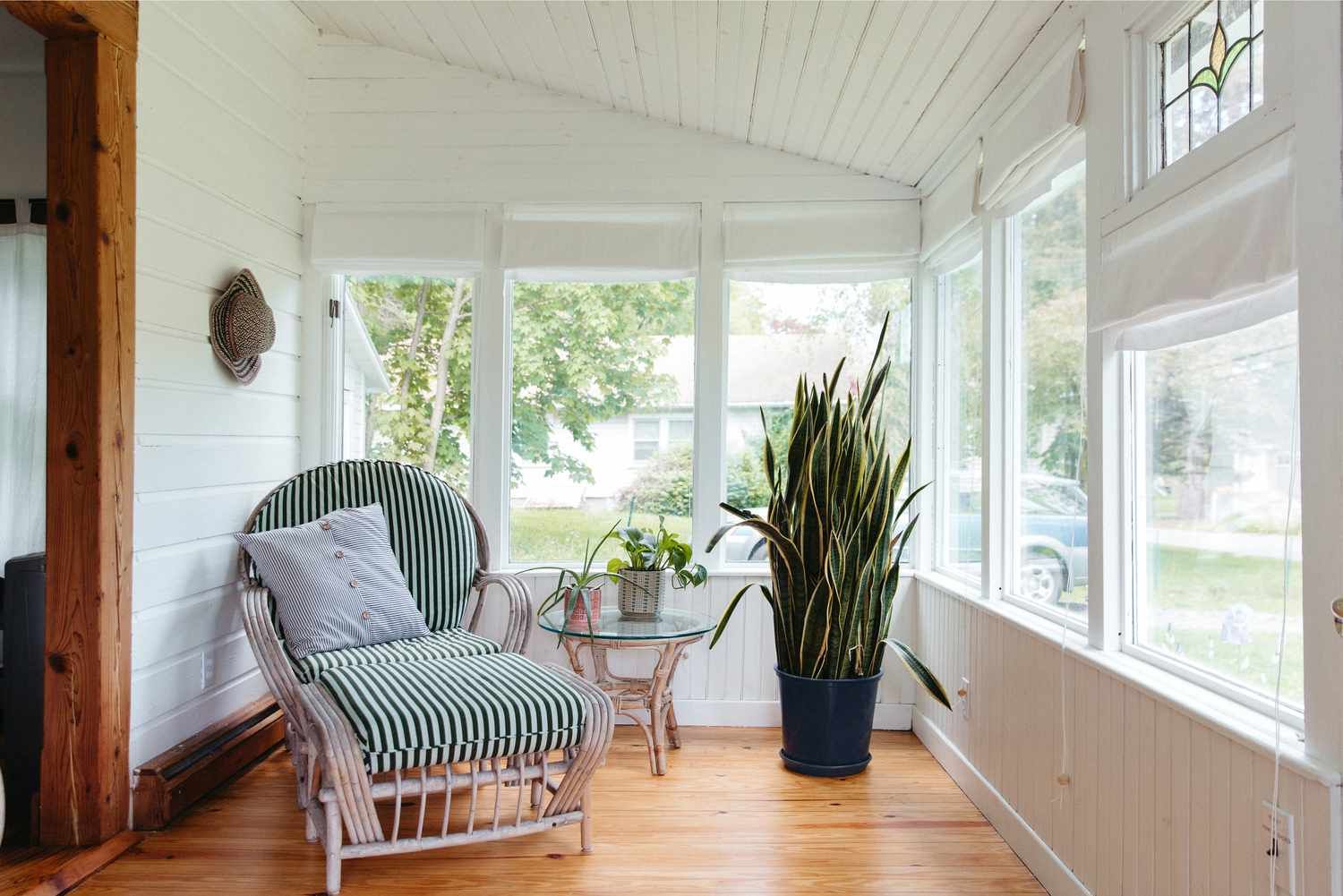 A screened in porch with a chair and a potted plant.