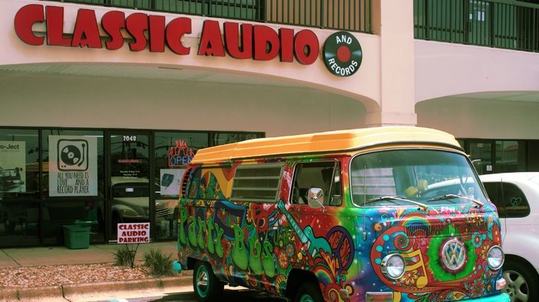 a colorful van is parked in front of a classic audio store