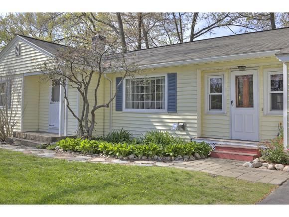 Yellow house with blue shutters, small tree, and green lawn.