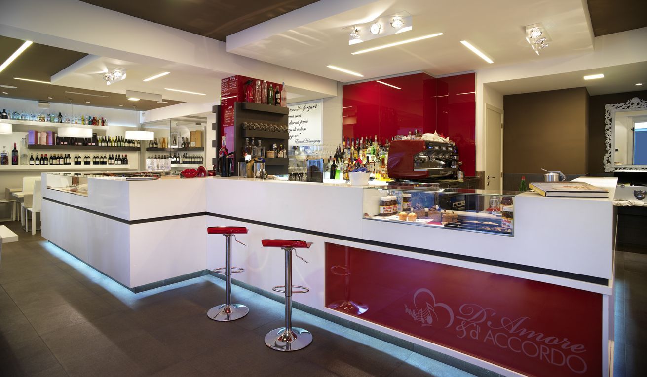 Un ristorante con un bar e sgabelli rossi e bianchi