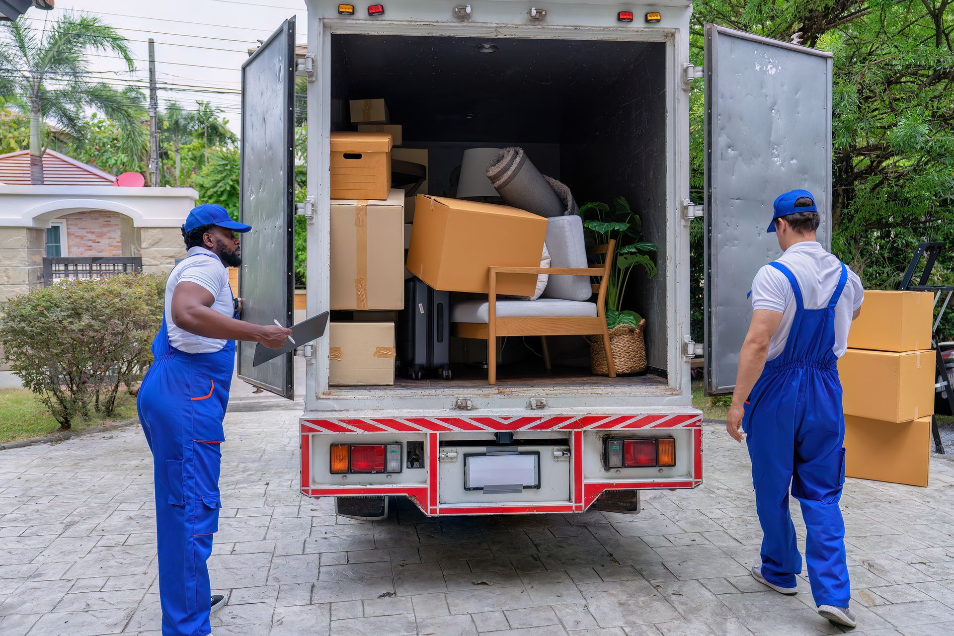 Movers unloading personal belongings from truck during professional moving service at new home site. Movers unloading personal belongings from truck during professional moving service at new home site.