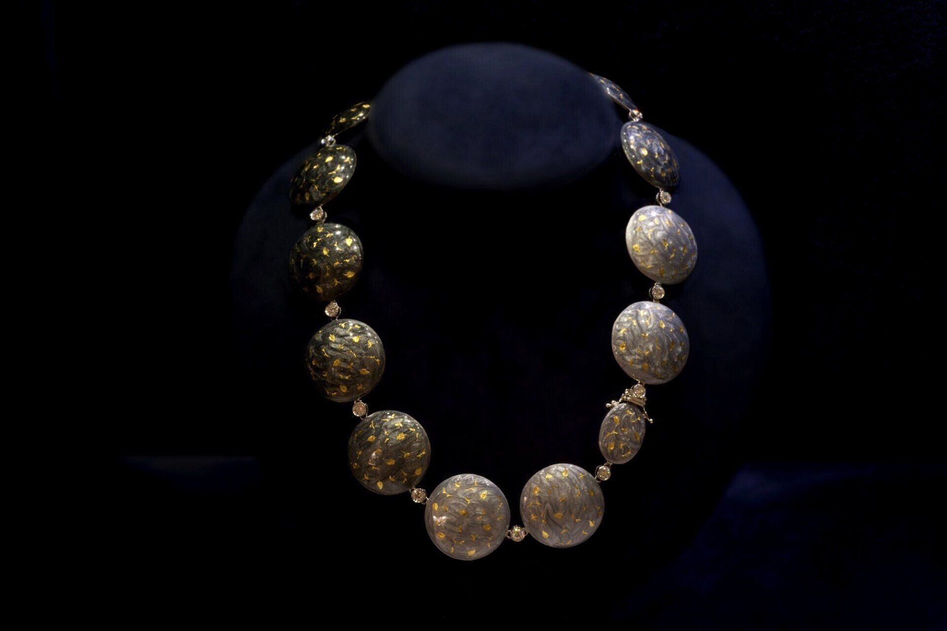 Collana di perline in oro e argento esposta su un busto blu scuro su sfondo nero Bruna Guglielmi Genova