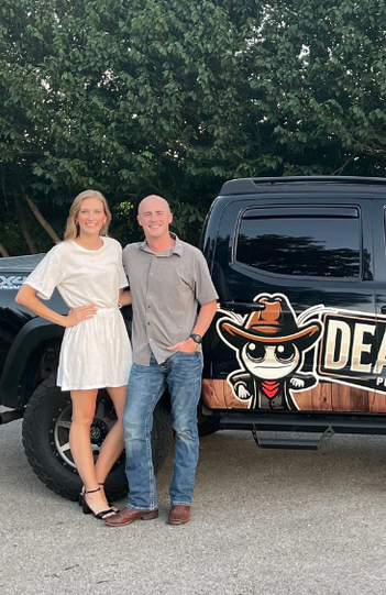 A man and a woman are standing in front of a truck.