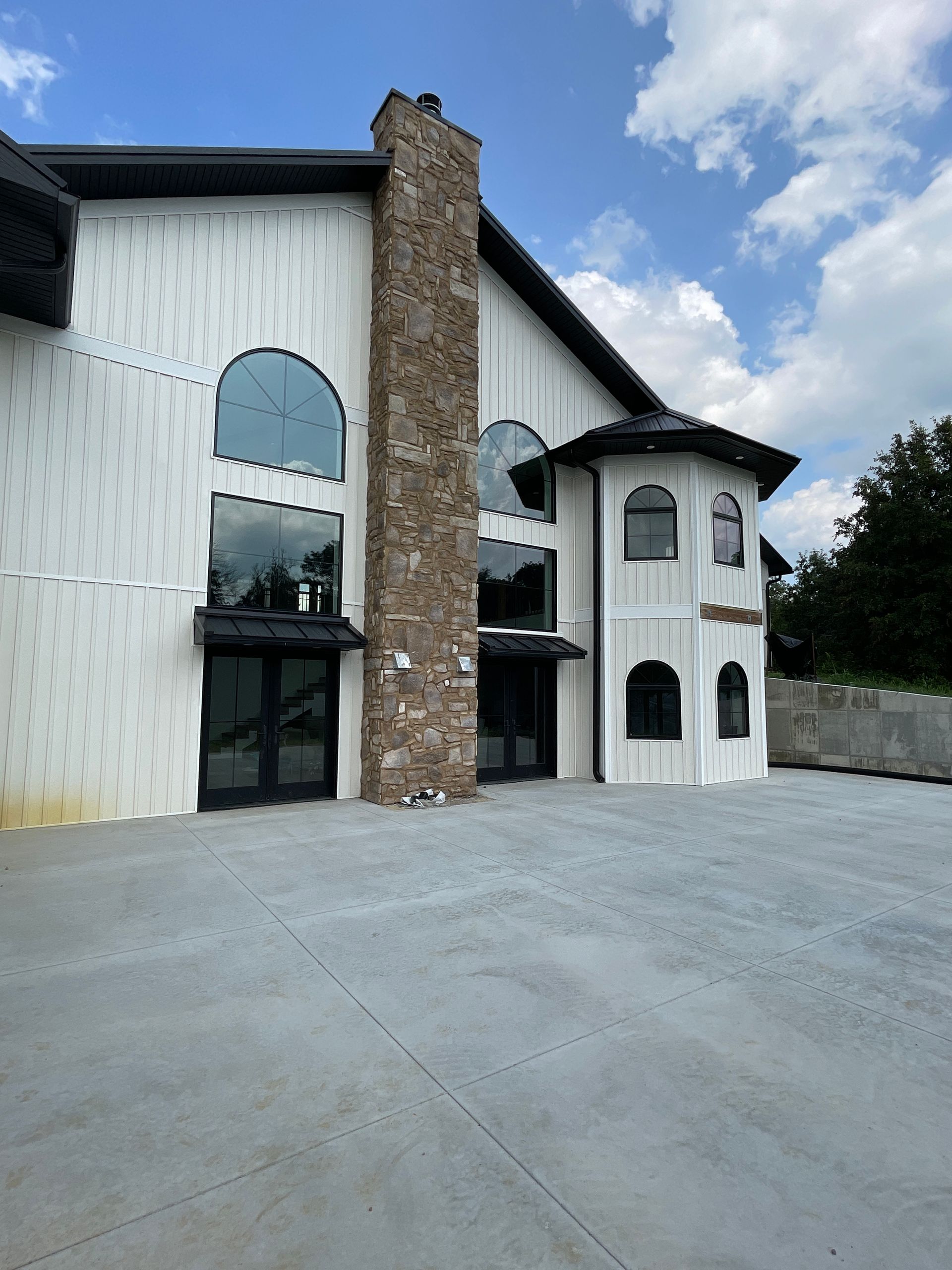 A large white building with a stone chimney and a lot of windows.