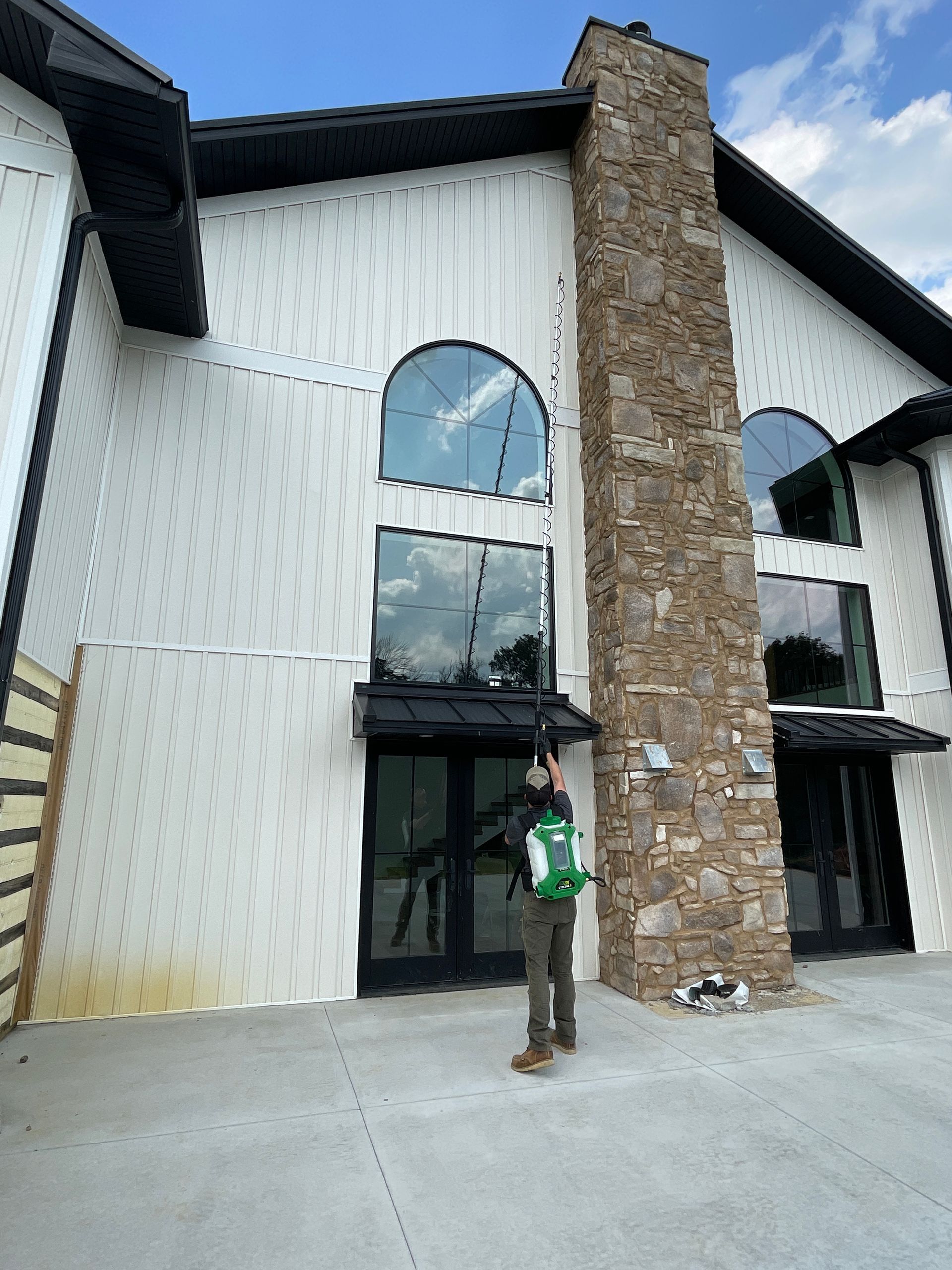A man is standing in front of a large white building with a stone chimney.