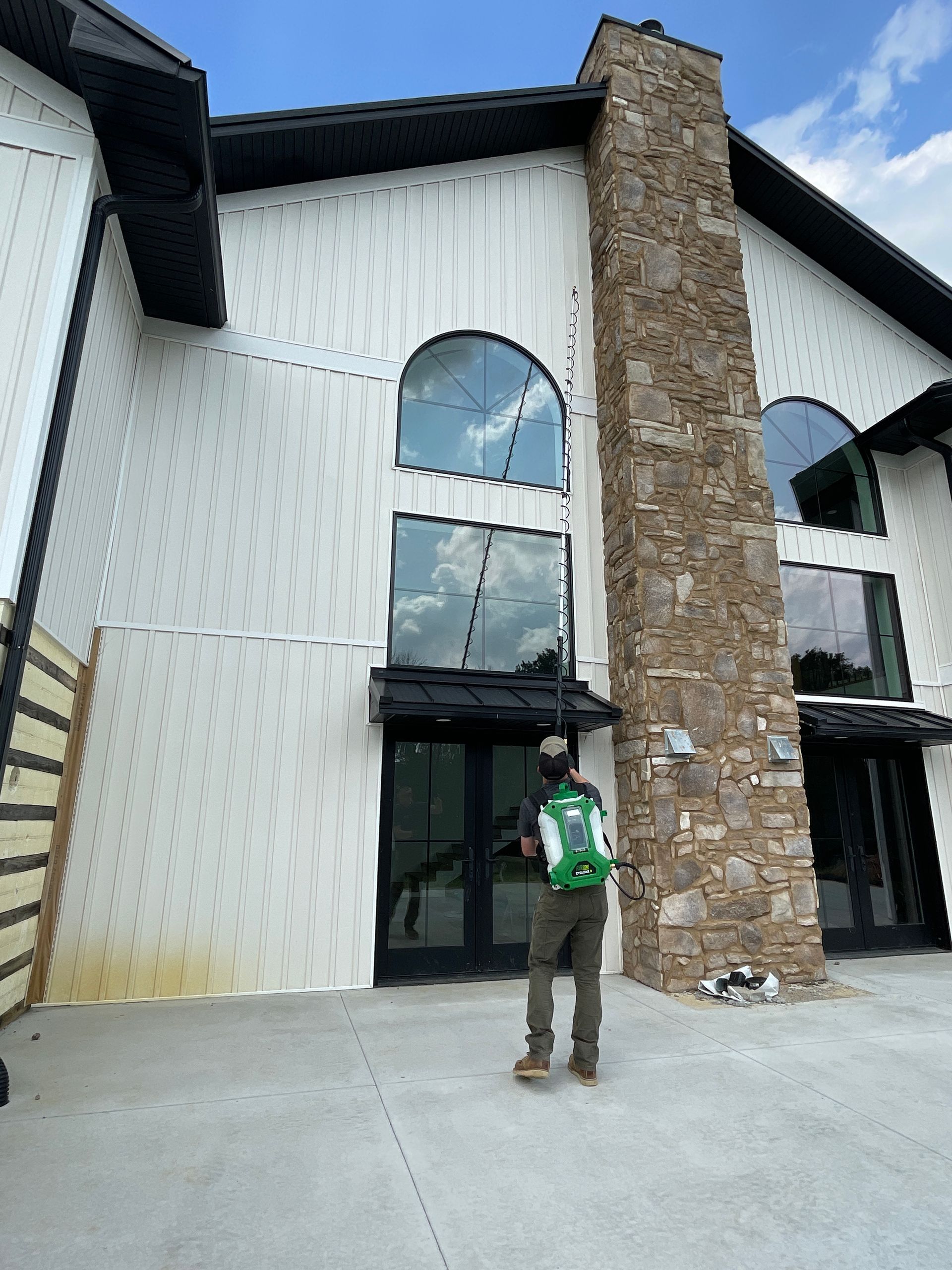 A man with a green backpack is standing in front of a large white building.