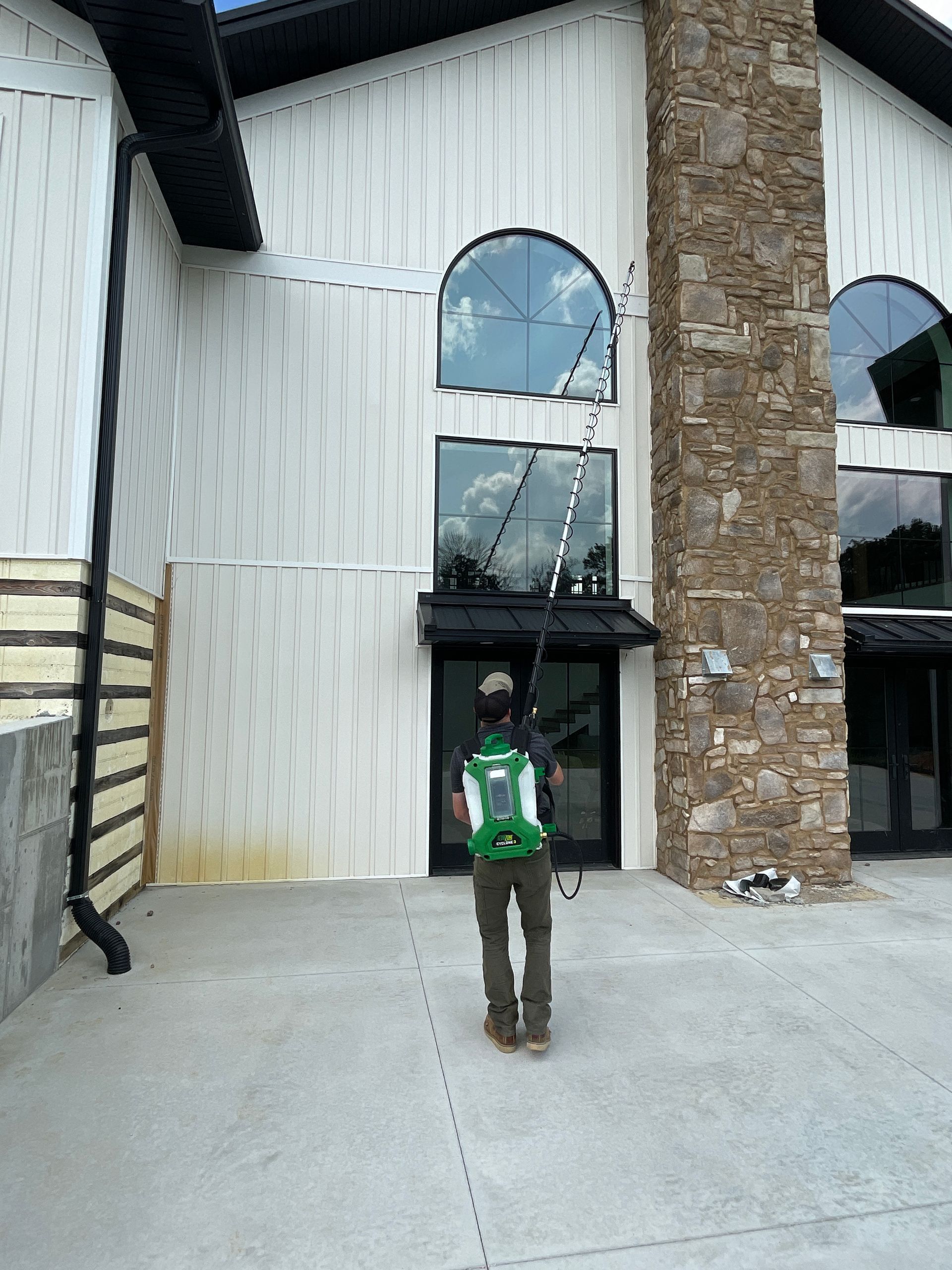 A man in a green backpack is standing in front of a large building.