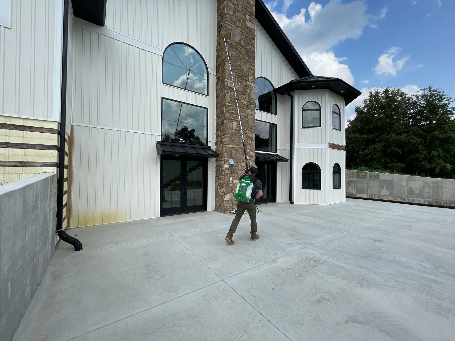 A man in a green backpack is walking in front of a large white building.