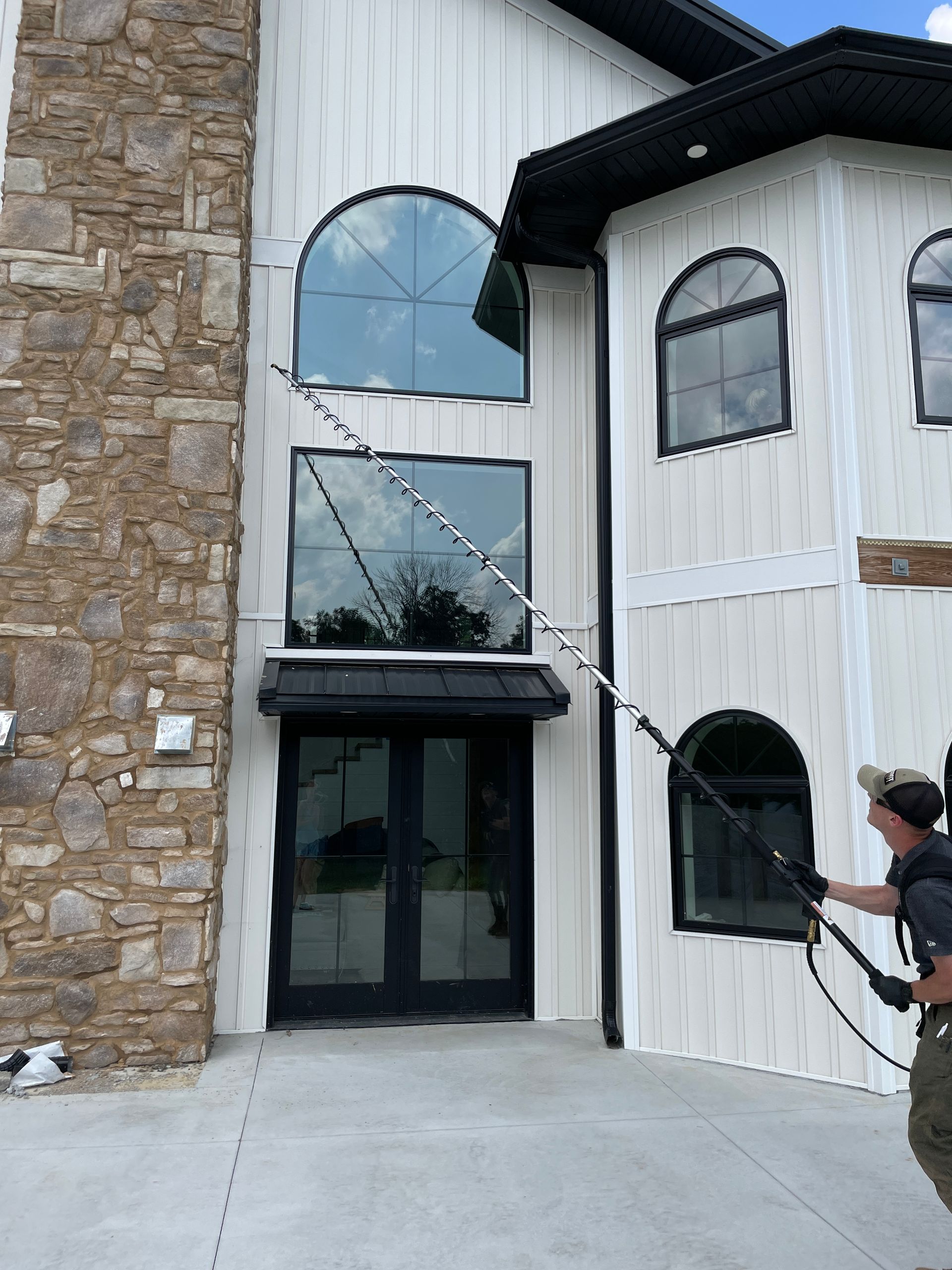 A man is cleaning the windows of a building with a hose.