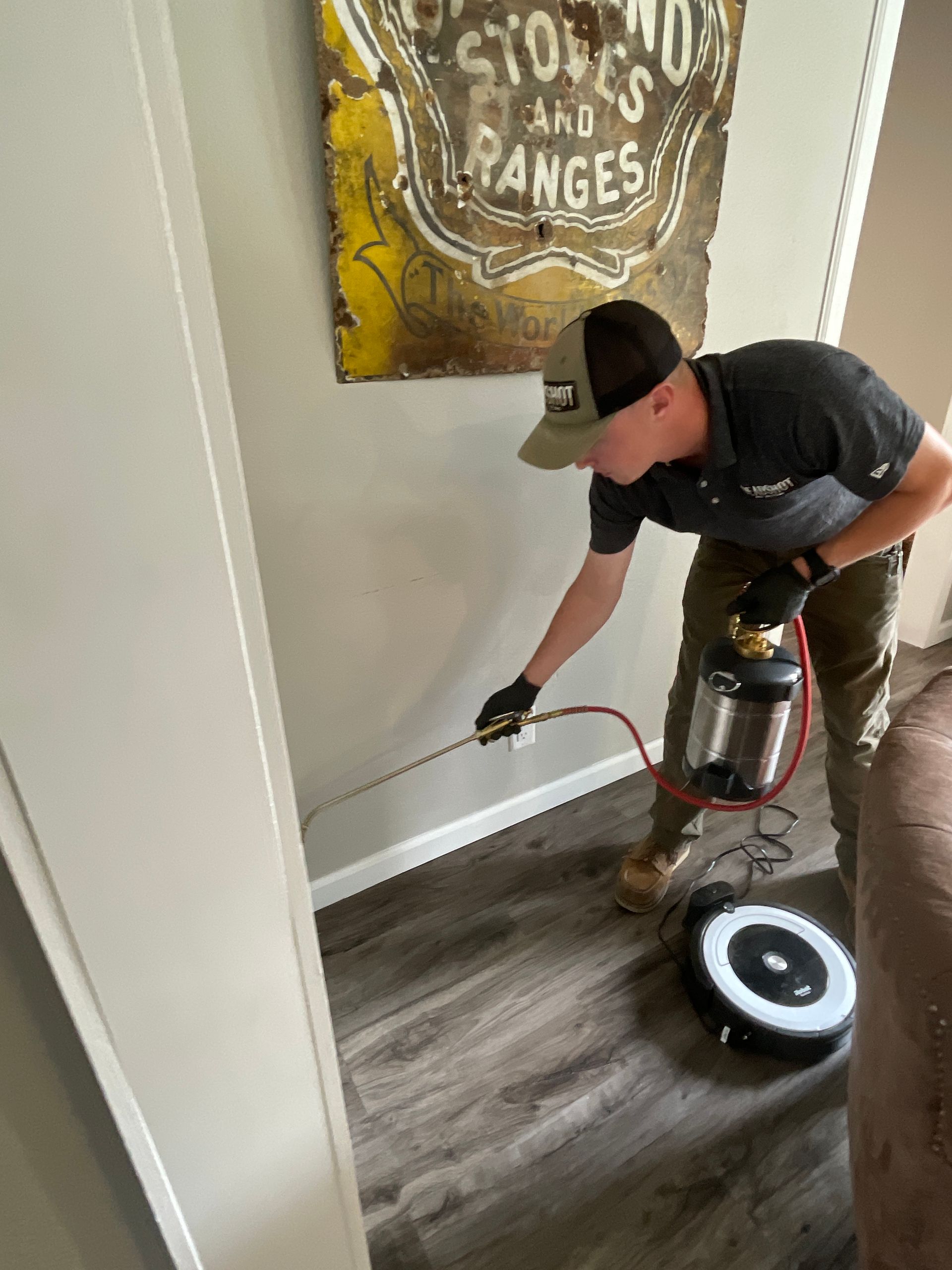 A man is spraying a wall with a sprayer in a living room.