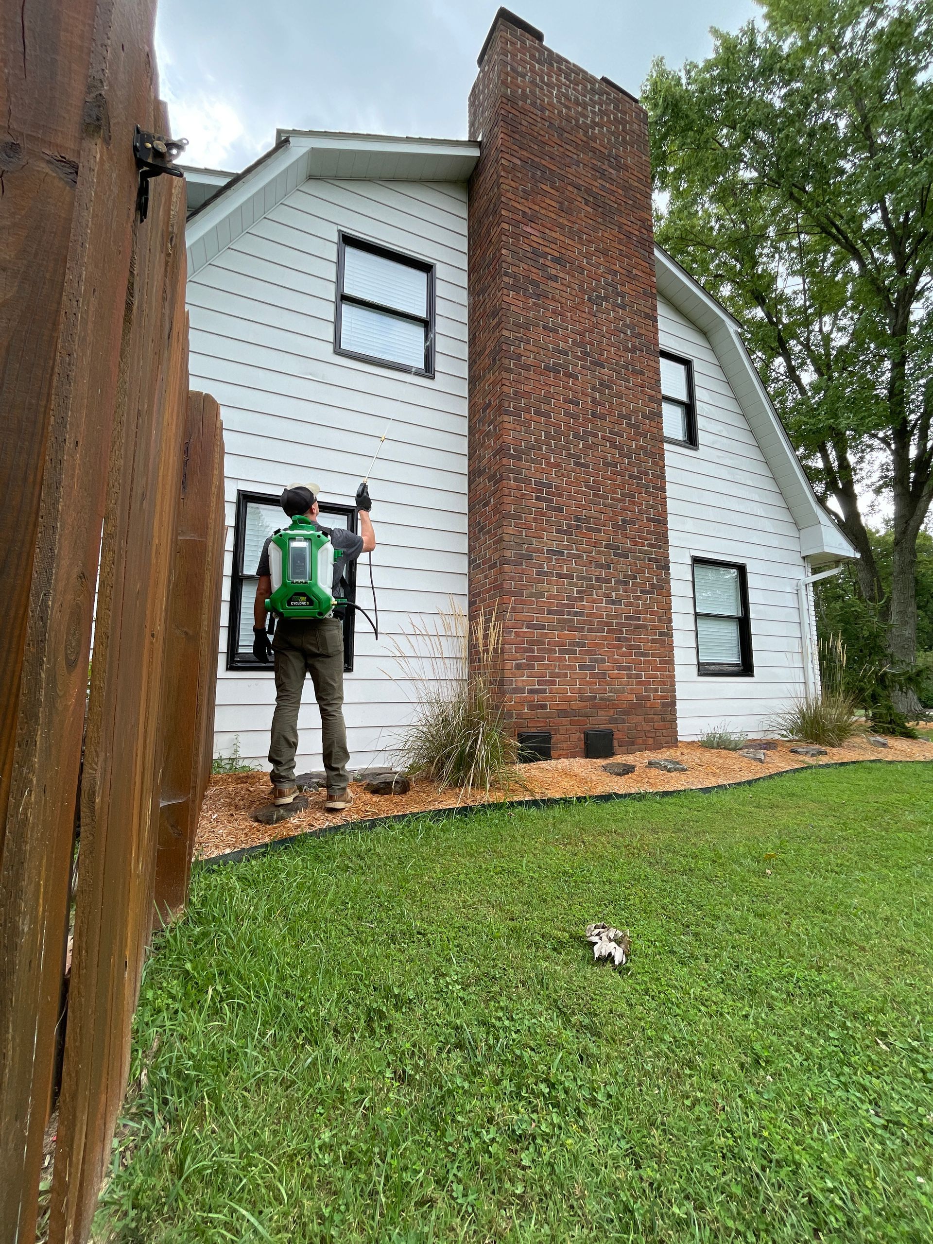 A man is installing a window on the side of a house.