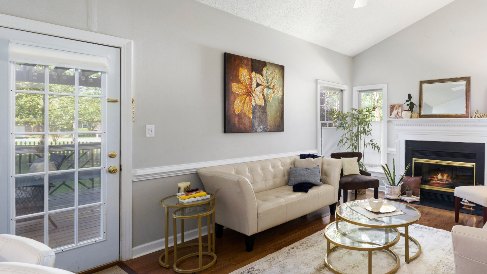 Living room with sofa, art, fireplace, door to patio. Soft light, neutral colors.
