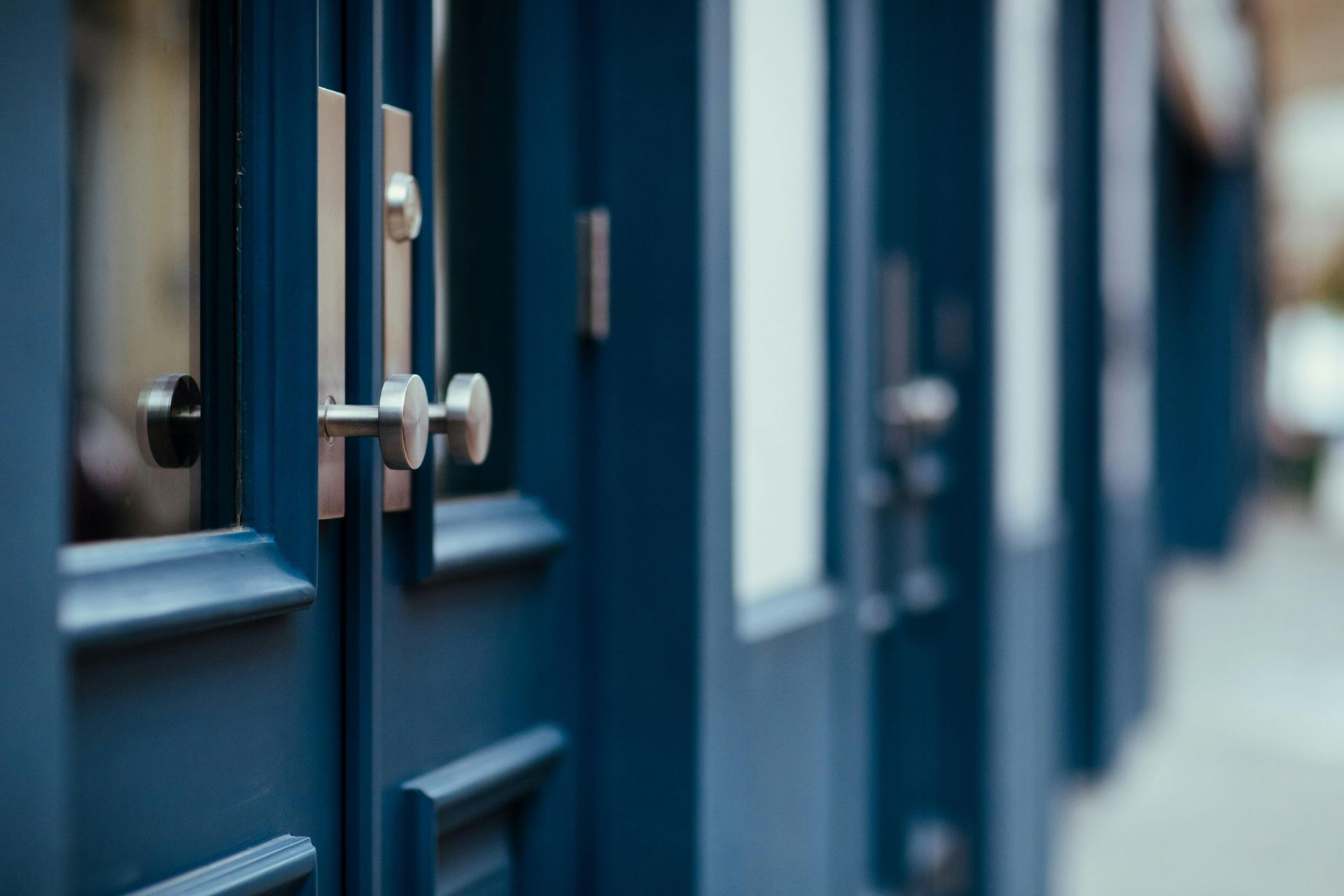Blue doors with silver handles and small windows, in an urban setting.