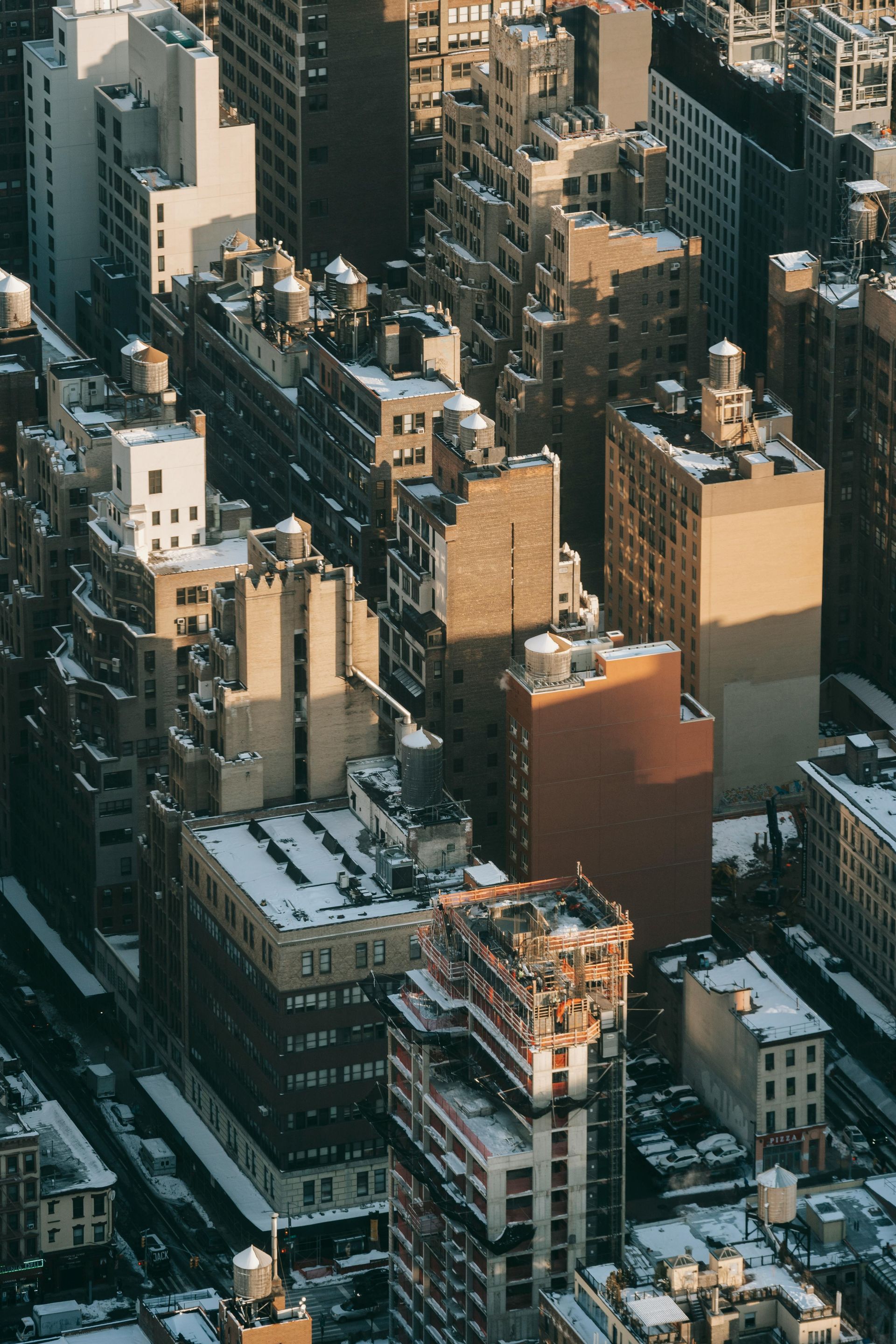 Aerial view of New York City buildings, showing rooftops with snow, and varying brown and beige facades.