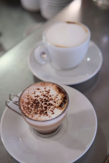 Due tazze di caffè su piattini, una con latte schiumato e cacao, l'altra con cappuccino.