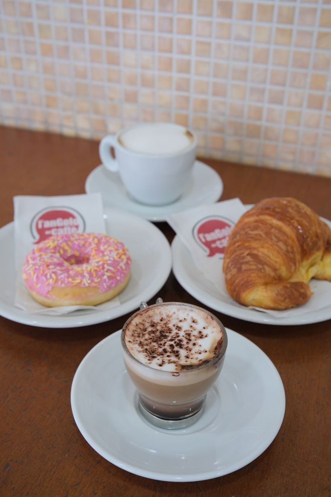 Cappuccino, ciambella e croissant con bevande al caffè, su un tavolo.