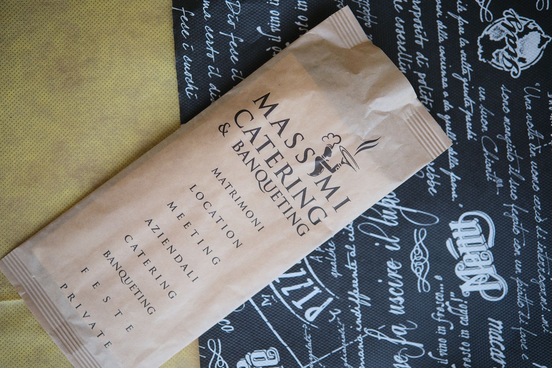 Una confezione di Massimi Catering & Banqueting su sfondo fantasia.