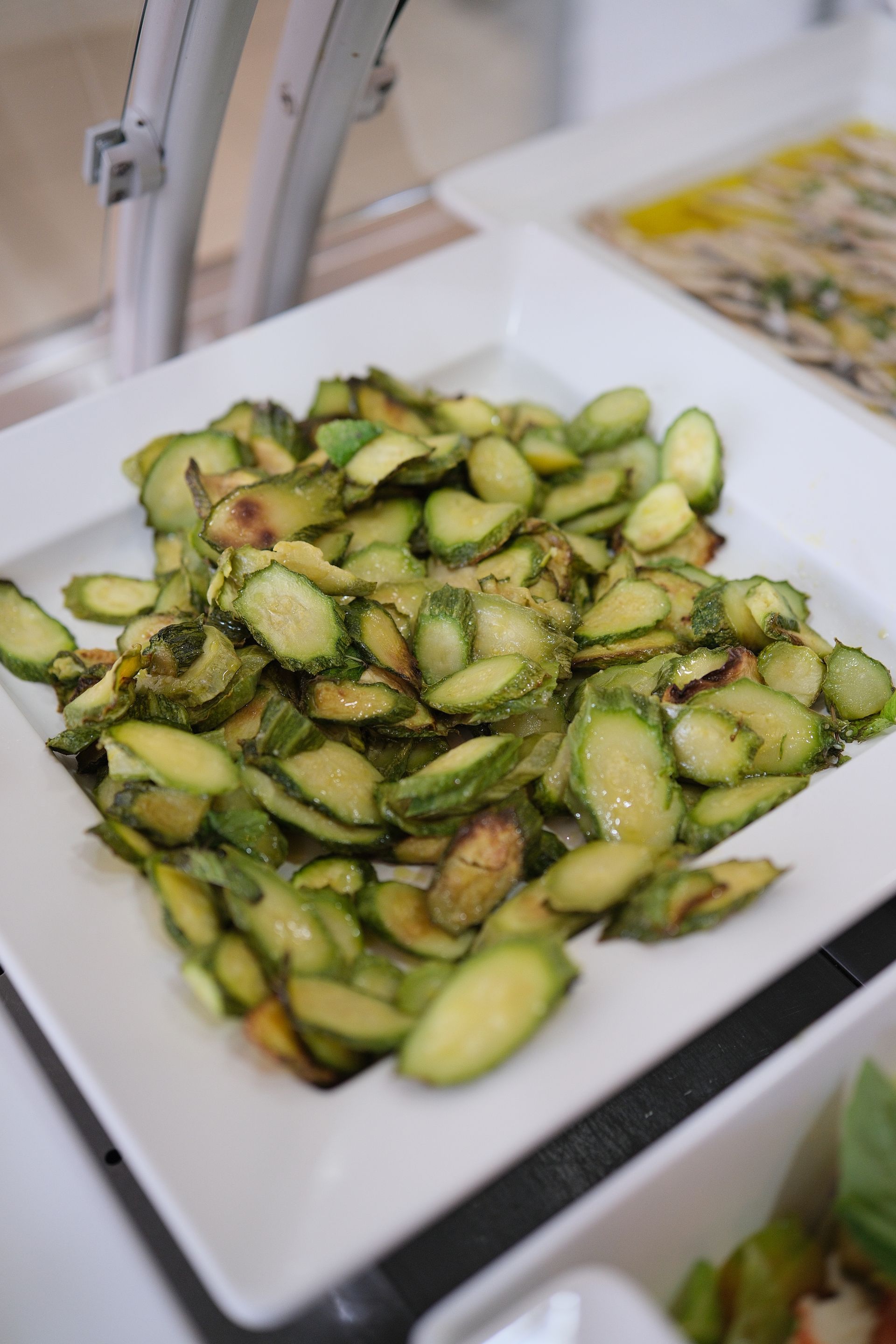 Asparagi verdi affettati su un piatto quadrato bianco, parte di un buffet.