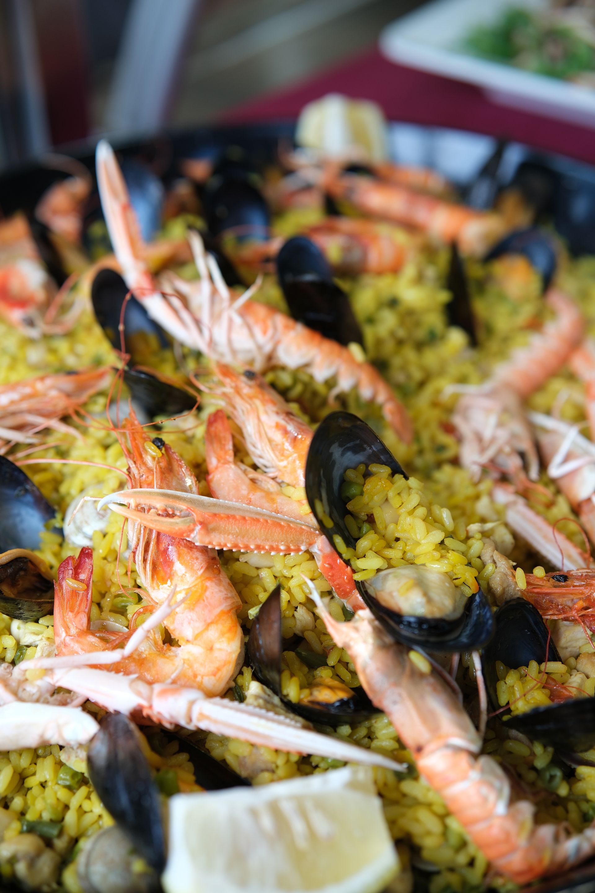 Paella di frutti di mare con gamberi, cozze e guarnizione di limone in una padella grande.