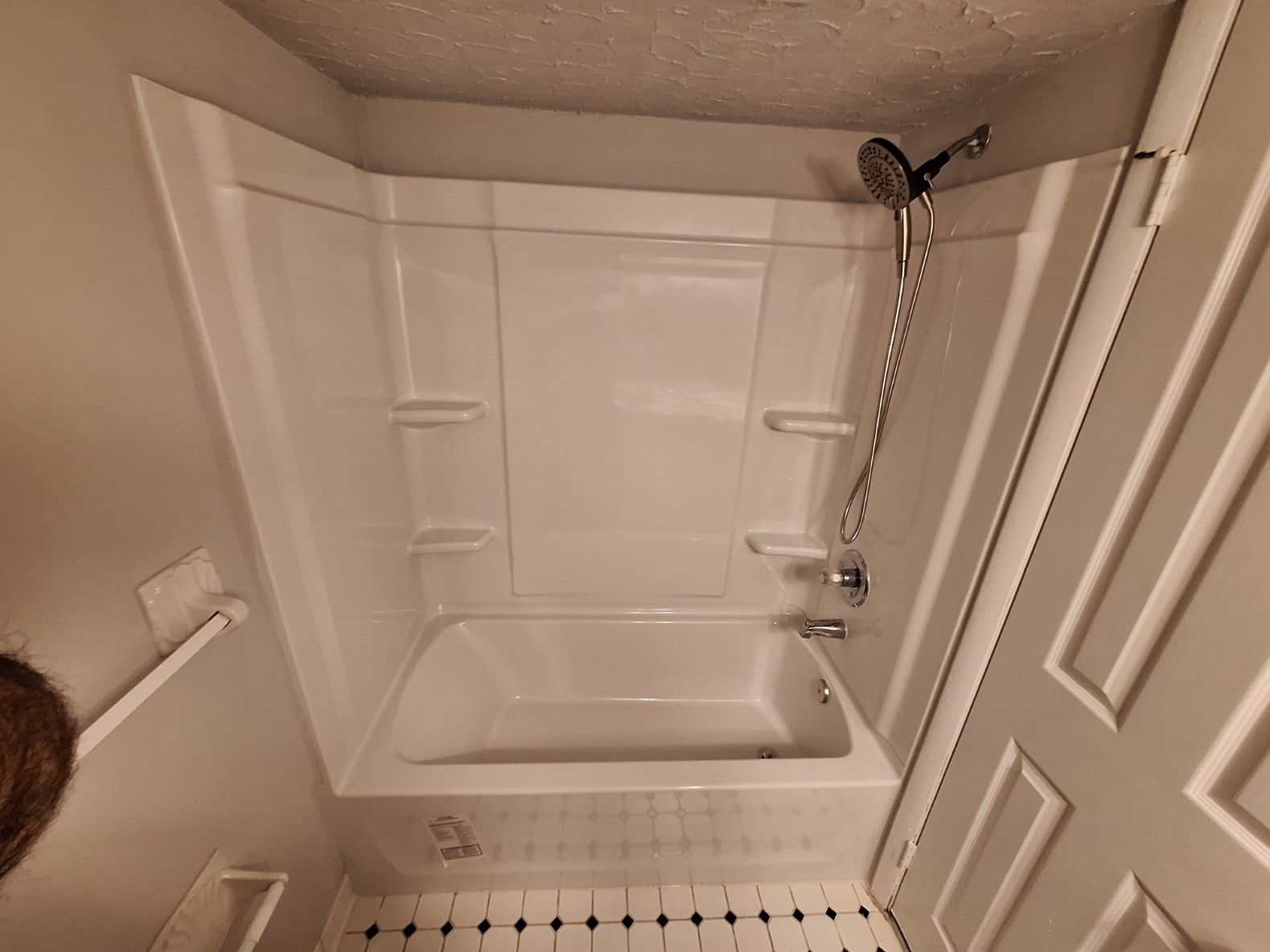 Copper and white PVC plumbing pipes installed on a white wall above a concrete floor, featuring a central brass valve.