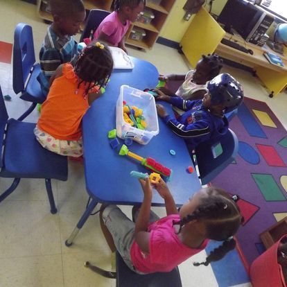 A group of children are playing with toys at a table
