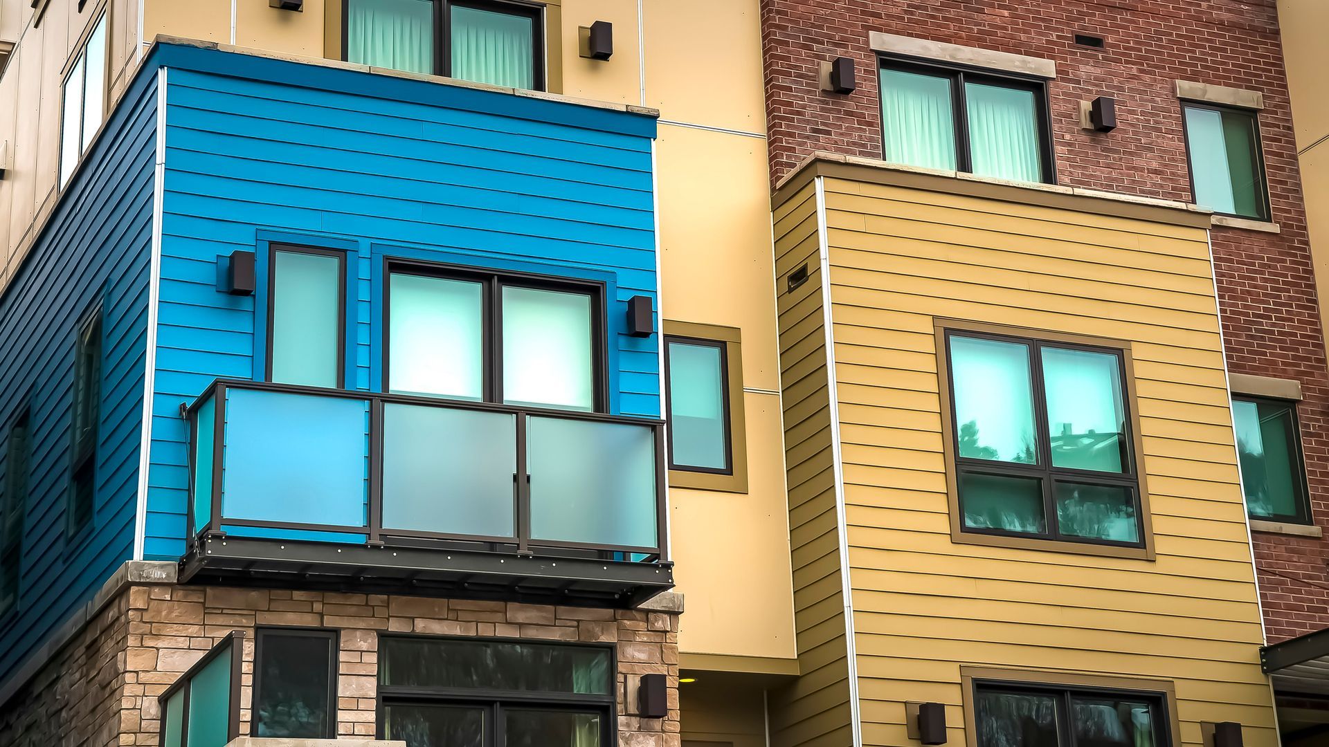 A blue and yellow building with a balcony on the second floor.