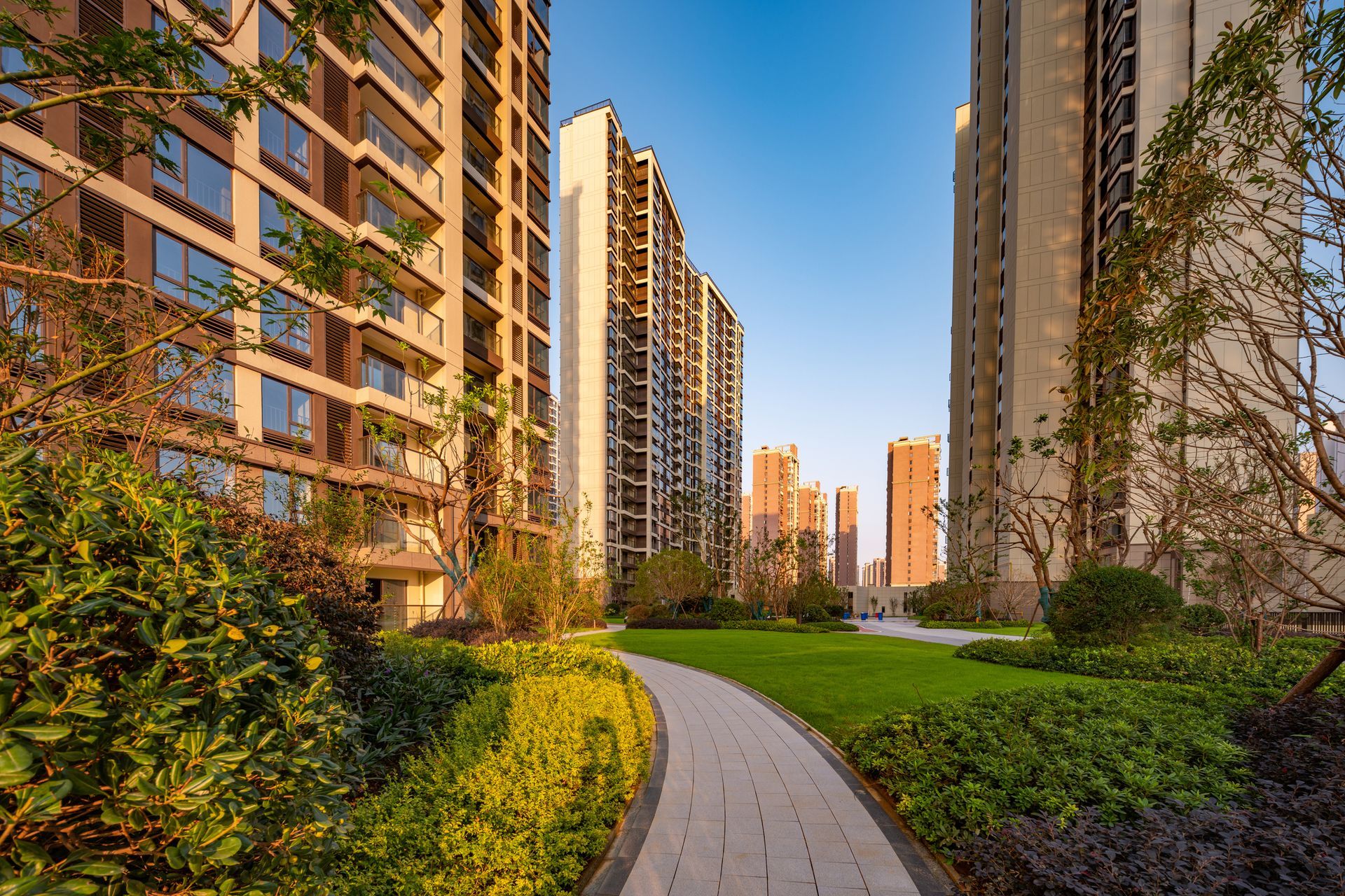A path leading to a row of tall buildings in a residential area.