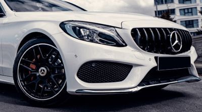 a white mercedes benz c class is parked on the side of the road .