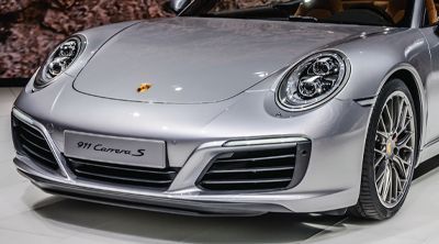 a silver porsche 911 carrera s is parked on a showroom floor .