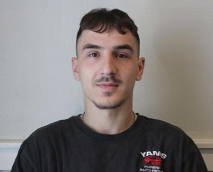A young man with a beard is wearing a yanis t-shirt.