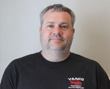 A man is wearing a yanis auto repair shirt