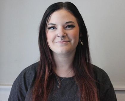 A woman with long hair and a nose ring is smiling for the camera.