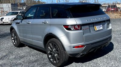 Silver Range Rover SUV with black roof and wheels parked on gravel.