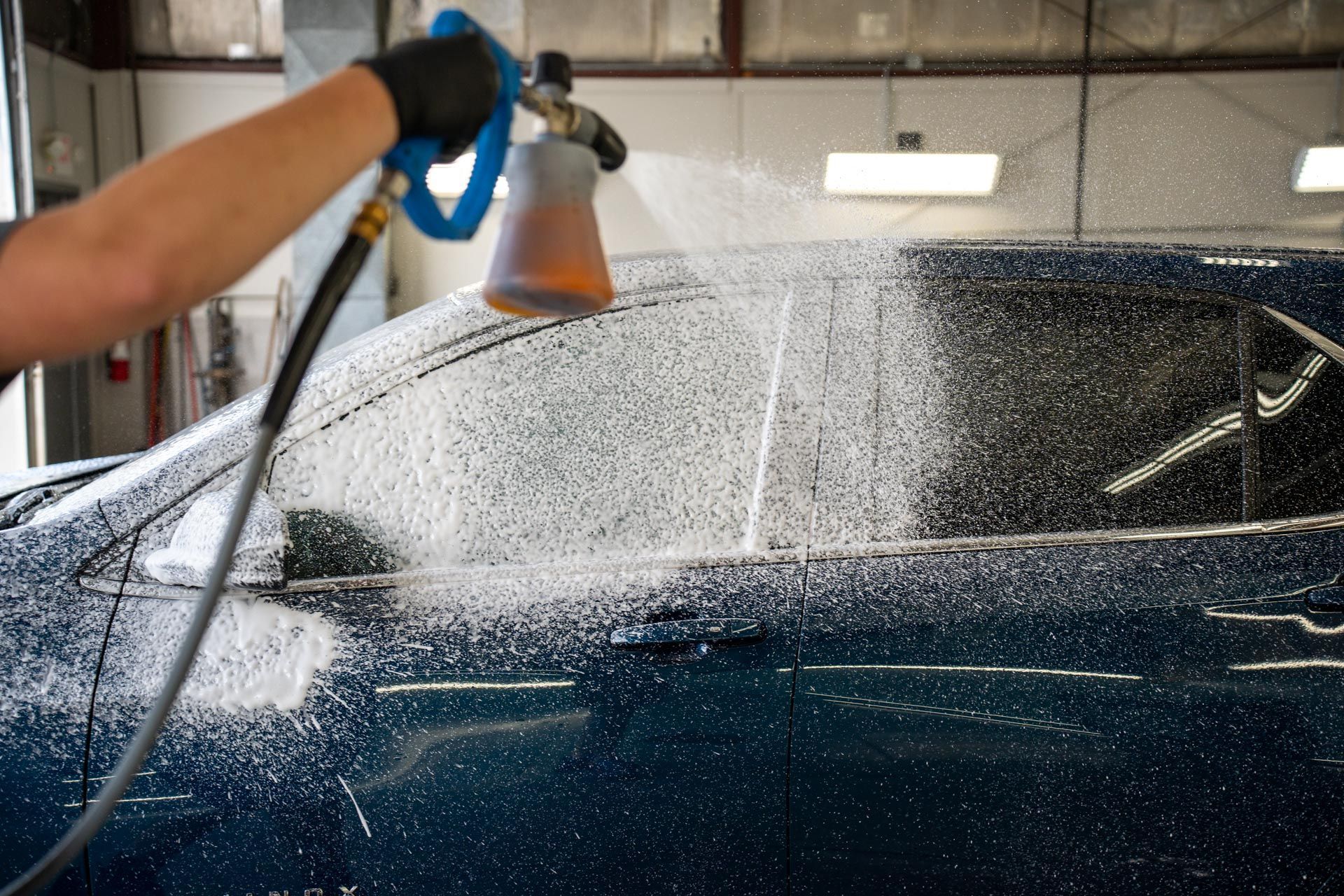 A person is washing a car with a foam sprayer.