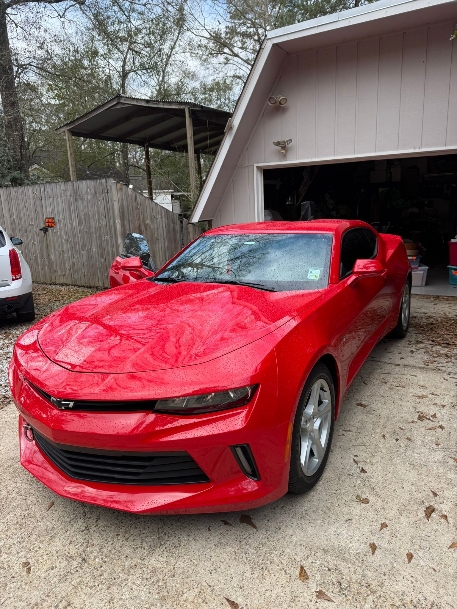 A red car is parked in front of a garage.