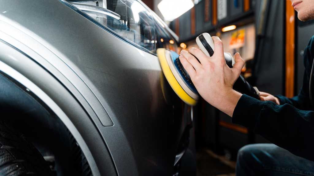 A man is polishing a car with a sponge.
