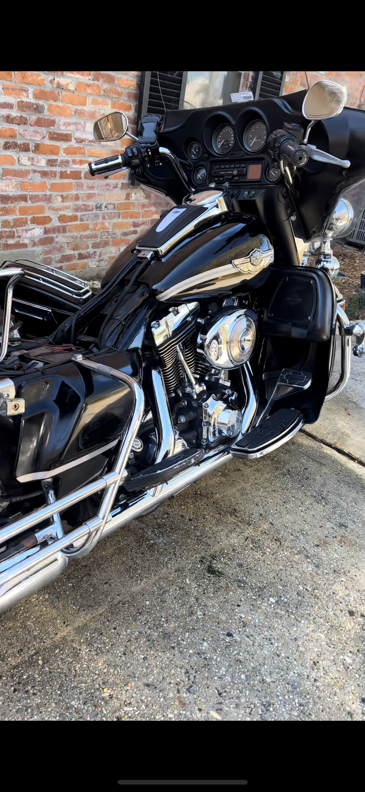 A black harley davidson motorcycle is parked in front of a brick building.
