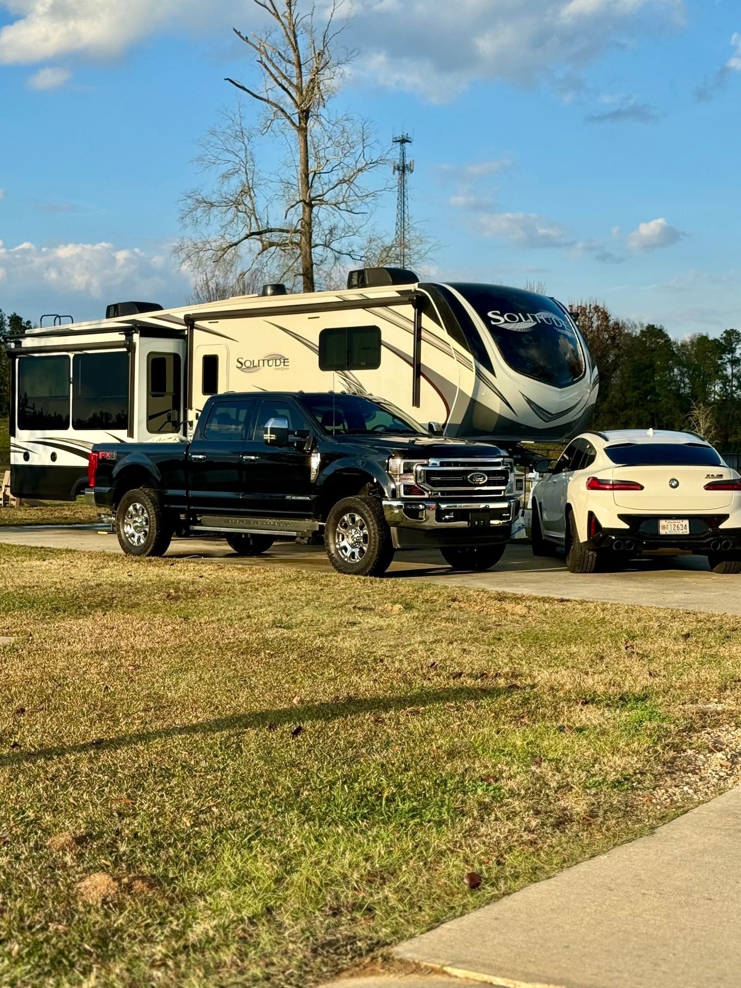 A truck and a car are parked in front of a rv.