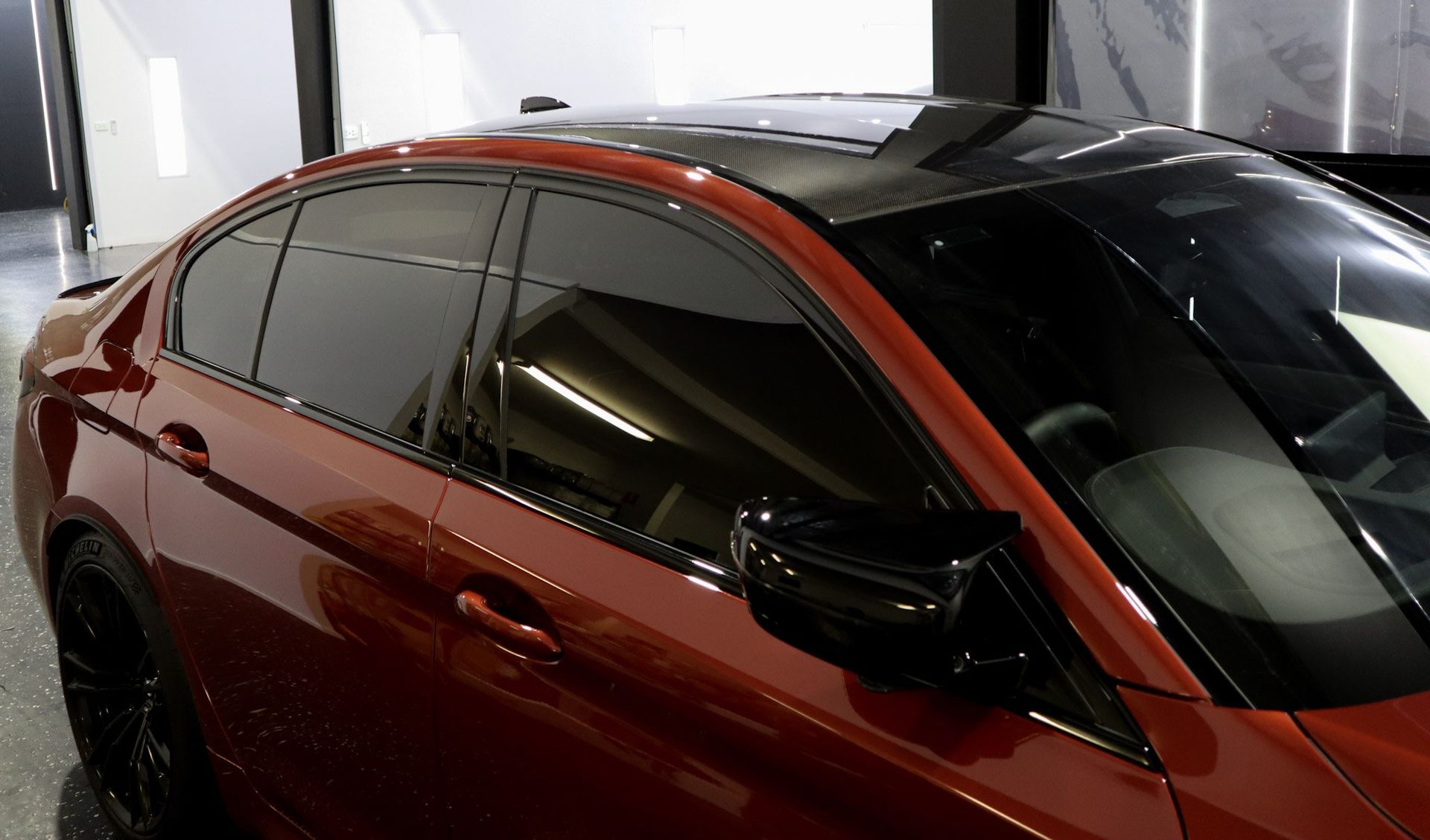 A red car with a black roof is parked in a garage