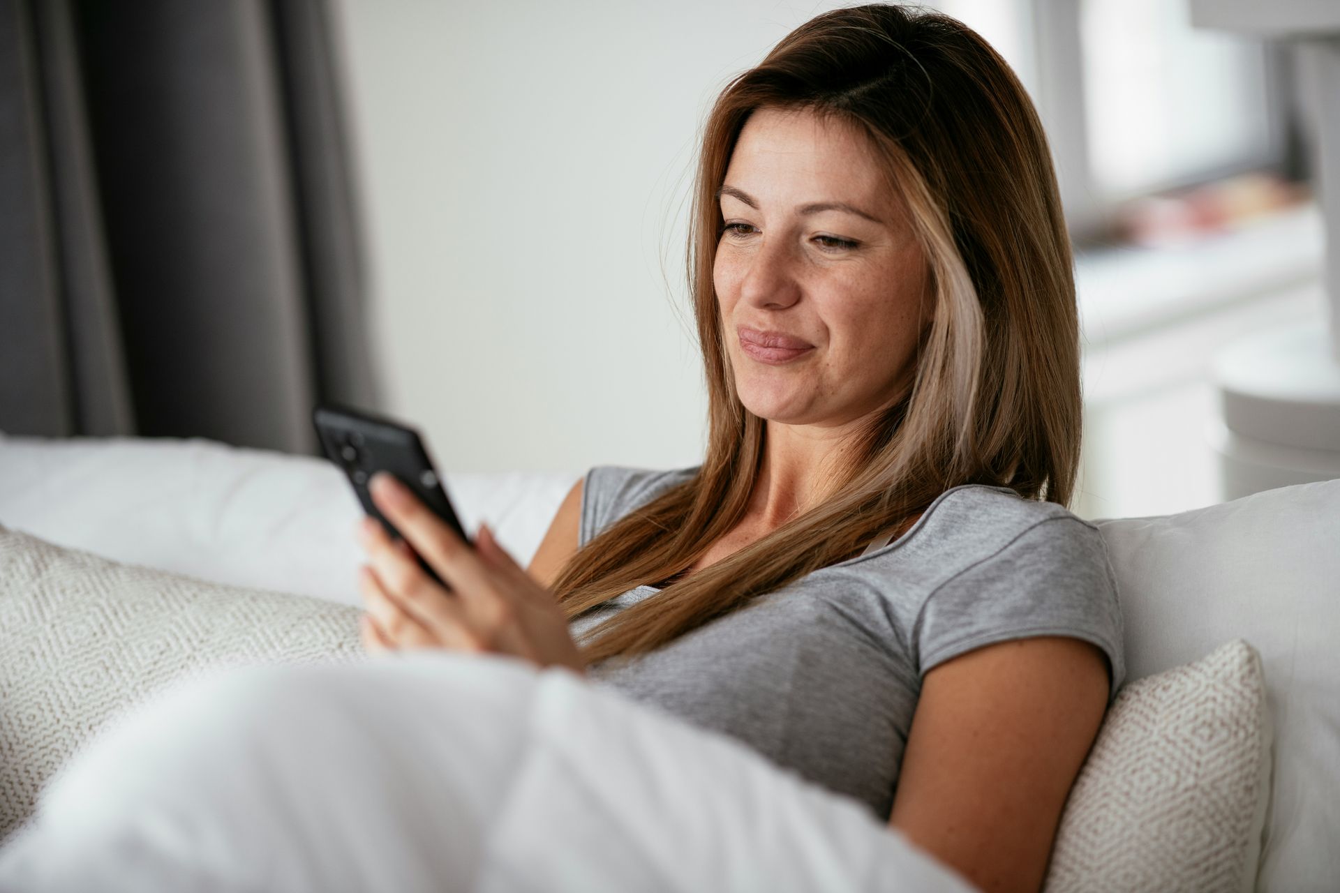 Woman using her phone to schedule a Myofascial Release session in Las Vegas for stress and pain relief.
