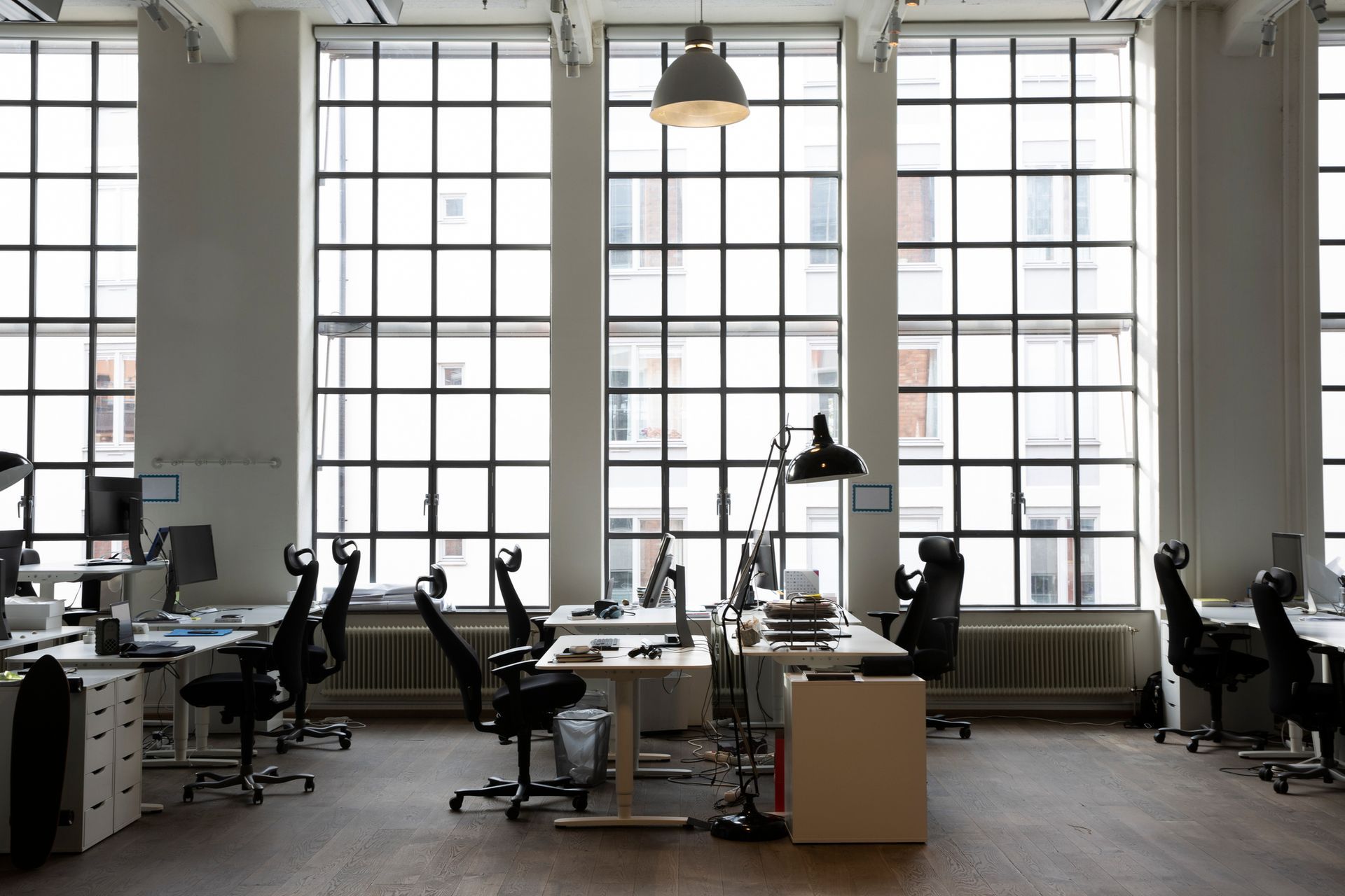 The interior of a creative office with open cubicles and chairs, in front of a big and wide window.