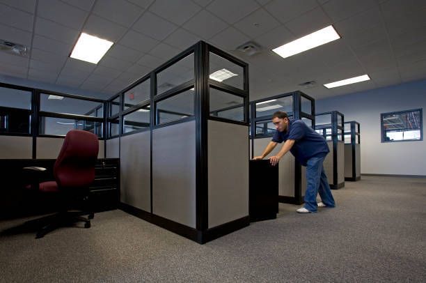 Person moving a drawer inside an empty office cubicle area