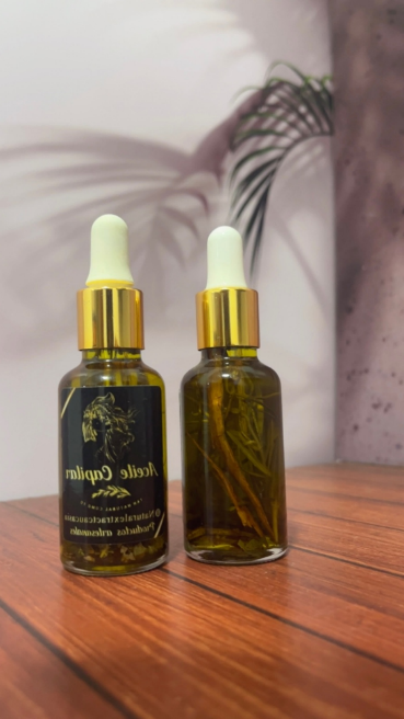 Dos frascos cuentagotas de vidrio ámbar llenos de aceite de hierbas reposan sobre una superficie de madera con un fondo neutro.
