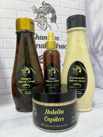 Cuatro productos para el cuidado del cabello con la marca en color dorado y negro, expuestos sobre una superficie blanca con un fondo de ladrillo blanco.