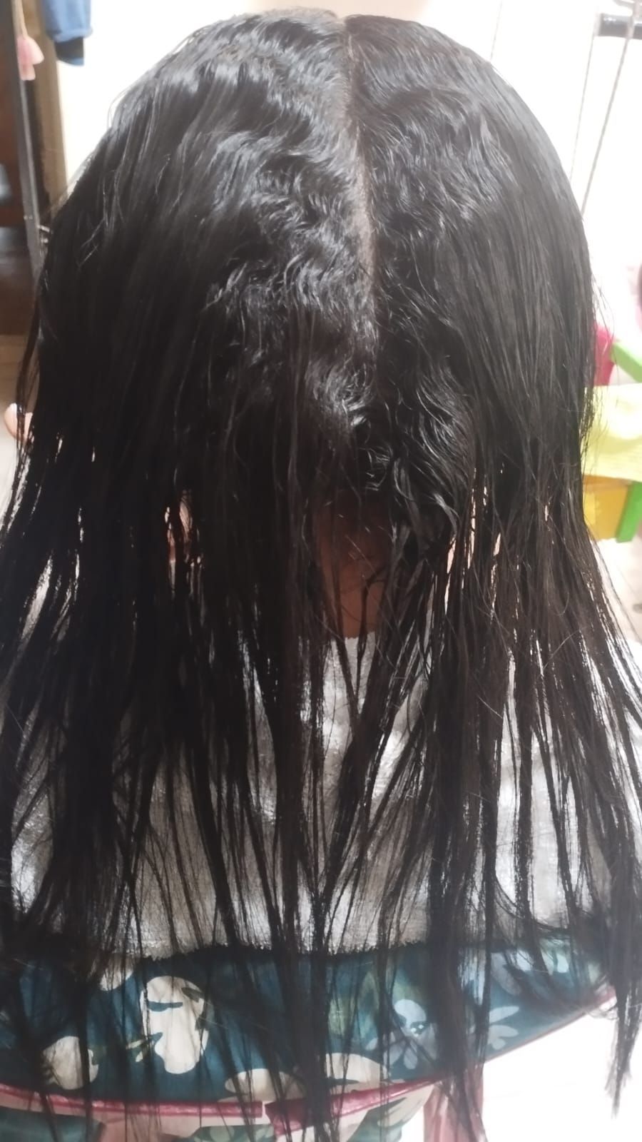 Vista posterior de una melena larga, lisa y oscura con textura visible producida por el uso de herramientas de calor, en un salón de belleza.